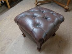 A brown button leather footstool on legs