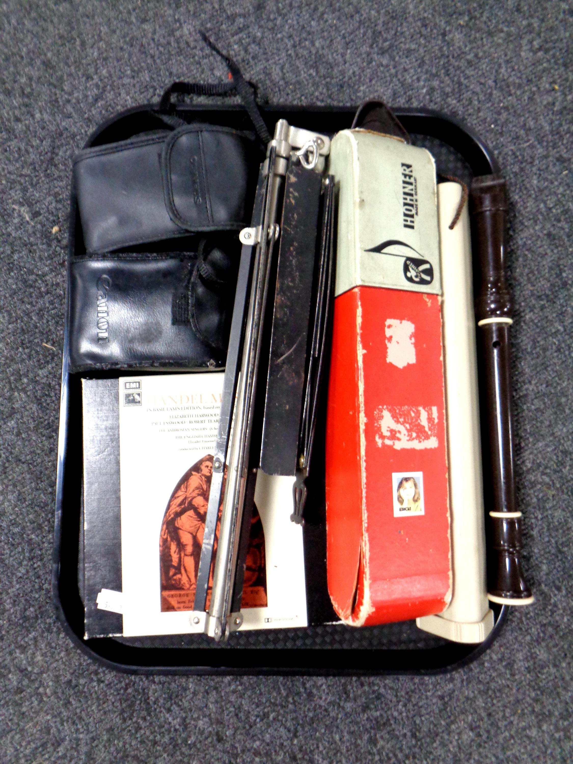 A tray containing cameras, music stand, Hohner melodica,