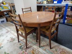 A 20th century G-Plan circular teak extending dining table together with a set of three ladder back