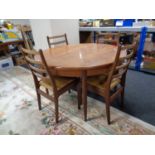 A 20th century G-Plan circular teak extending dining table together with a set of three ladder back