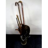 A brass embossed stick stand containing a quantity of walking sticks and crooks,