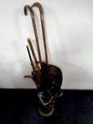 A brass embossed stick stand containing a quantity of walking sticks and crooks,