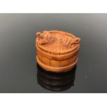 A carved hardwood netsuke - turtles in a barrel