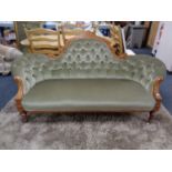 A Victorian inlaid mahogany shaped back settee upholstered in a green button dralon