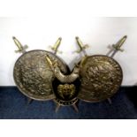 A pair of brass embossed plaques with ornamental swords together with a brass breast plate with