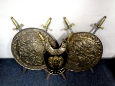 A pair of brass embossed plaques with ornamental swords together with a brass breast plate with