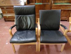A pair of wood framed armchairs with black leather cushions