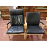 A pair of wood framed armchairs with black leather cushions