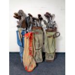 Four 20th century golf bags containing a quantity of vintage irons and drivers