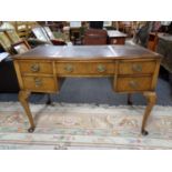 An Edwardian walnut writing desk on Queen Anne legs with three leather inset panels