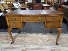 An Edwardian walnut writing desk on Queen Anne legs with three leather inset panels