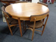 A 20th century circular teak G Plan dining table with four stowaway chairs
