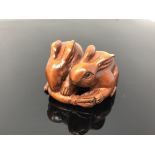 A carved hardwood netsuke - Two rabbits