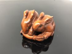 A carved hardwood netsuke - Two rabbits