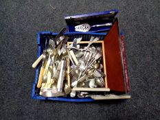 A basket of a large quantity of boxed and unboxed stainless steel and plated cutlery