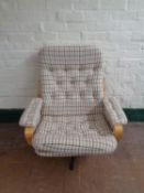 A late 20th century swivel armchair upholstered in a cream checked fabric on chrome base
