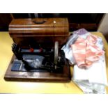An early 20th century cased hand sewing machine together with a small quantity of table linen