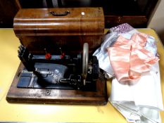 An early 20th century cased hand sewing machine together with a small quantity of table linen