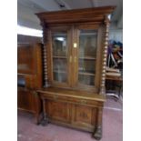 A 19th century oak double door bookcase with bobbin column supports,