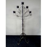 A wrought iron floor standing five way candle stand