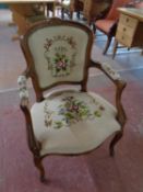 A carved beech framed French salon armchair upholstered in a tapestry fabric