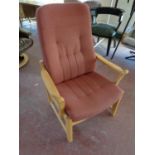 A wood framed armchair upholstered in a pink fabric