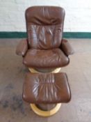 A brown leather swivel adjustable armchair with stool