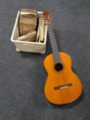 A box containing sheet music together with an acoustic guitar