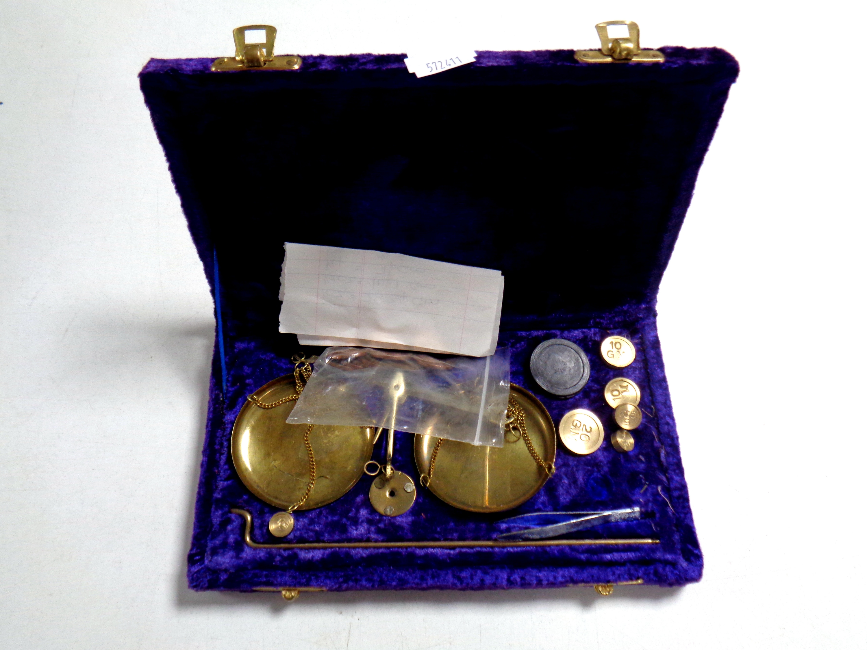A set of miniature brass balance scales with weights in a fitted purple velvet box