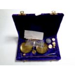 A set of miniature brass balance scales with weights in a fitted purple velvet box