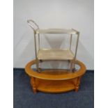 An oval glass topped coffee table with under shelf together with a gilt two tier tea trolley