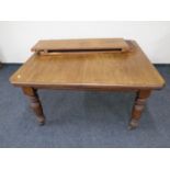 An Edwardian mahogany wind out dining table with two leaves