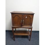 An Edwardian oak double door cabinet on raised legs with under shelf fitted two internal drawers