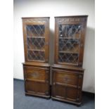 A pair of carved Jaycee oak corner display cabinets with leaded glass door above and panelled door