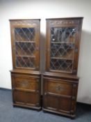 A pair of carved Jaycee oak corner display cabinets with leaded glass door above and panelled door