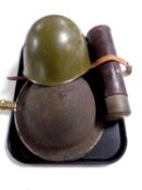 Two World War II tin helmets together with a vintage flask in leather sheath
