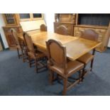 An early 20th century oak pull out dining table with checker board inlaid top on a heavily carved