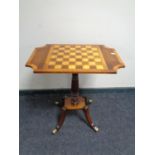 A Victorian style pedestal occasional table with chessboard top on brass feet