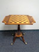 A Victorian style pedestal occasional table with chessboard top on brass feet