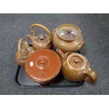 A tray containing antique and later pottery to include three teapots and two lidded storage jars