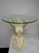 A contemporary glass topped occasional table on mermaid pedestal