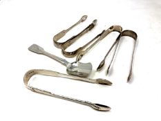 Five pairs of Georgian/William IV sugar tongs and a spoon,