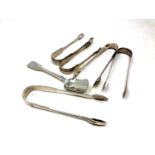 Five pairs of Georgian/William IV sugar tongs and a spoon,