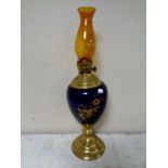 A Duplex brass and porcelain oil lamp with amber glass chimney