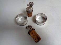 A pair of Sheffield silver napkin rings together with a pair of silver wine cork toppers