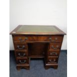 A reproduction mahogany lady's desk with green tooled leather top