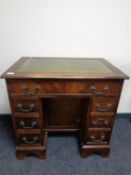 A reproduction mahogany lady's desk with green tooled leather top