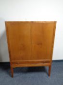 A mid century mahogany double door cabinet fitted a drawer