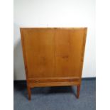 A mid century mahogany double door cabinet fitted a drawer