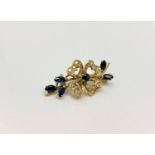 An 18ct gold diamond and sapphire brooch, 7.2g, width 38 mm.